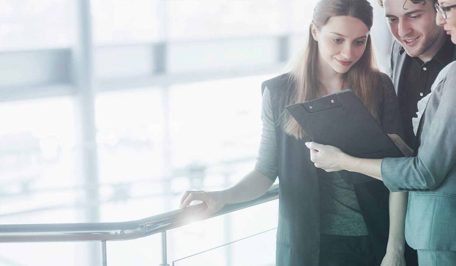 group of workers looking at a clipboard by a large window