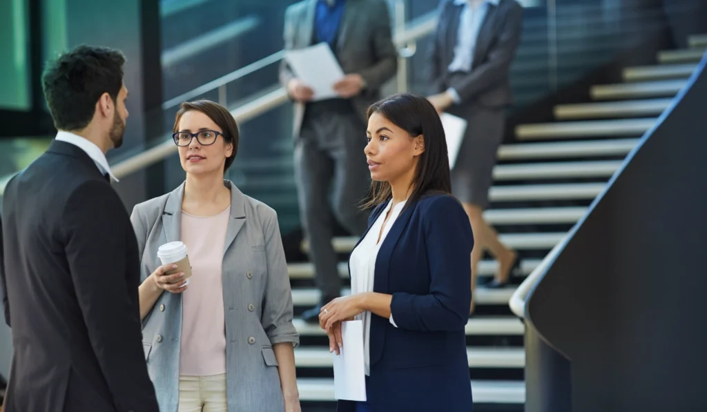 group of lawyers in professional attire at the bottom of stairs in conversation