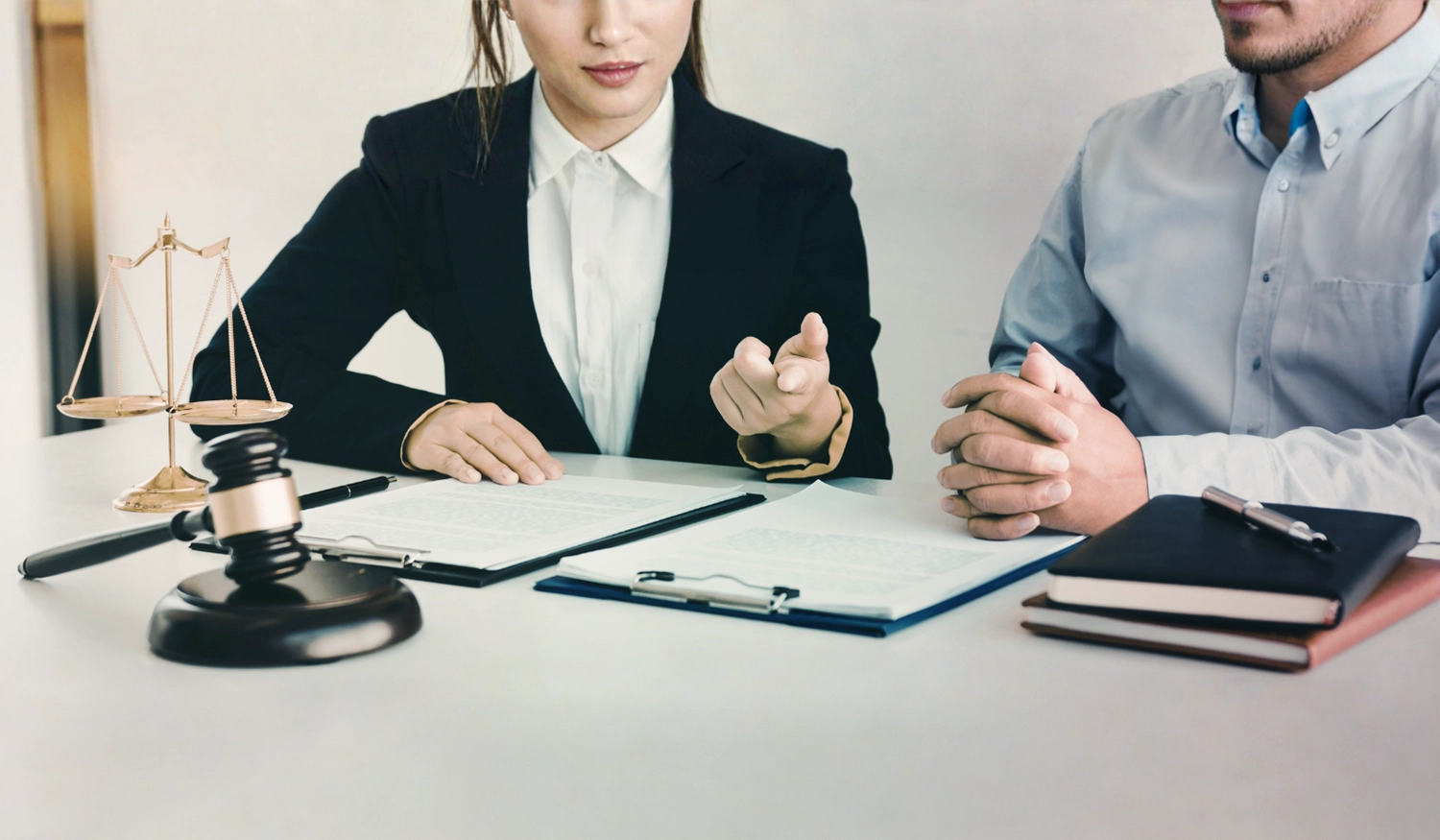 man an woman sitting a desk looking at legal papers and documents. scale and phone on desk
